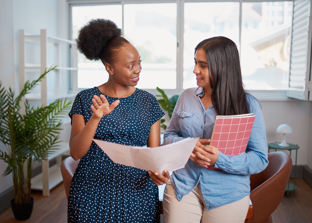 Two women looking at papers and talking